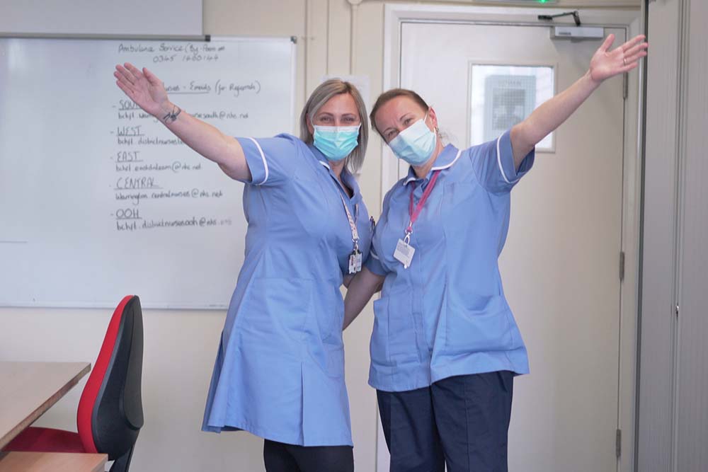 Two NHS care workers smiling and posing for a photo