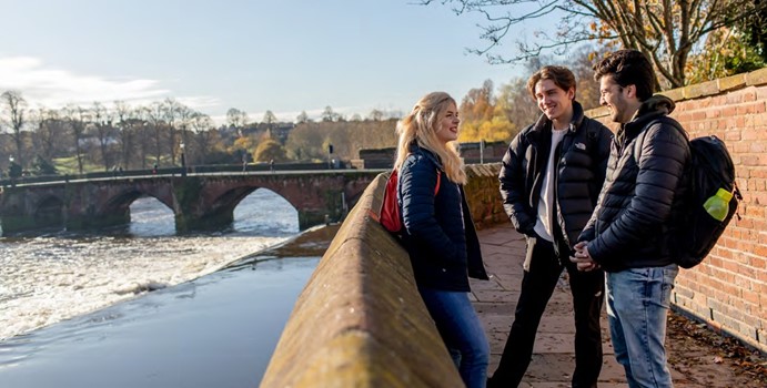 Image of students talking by a river